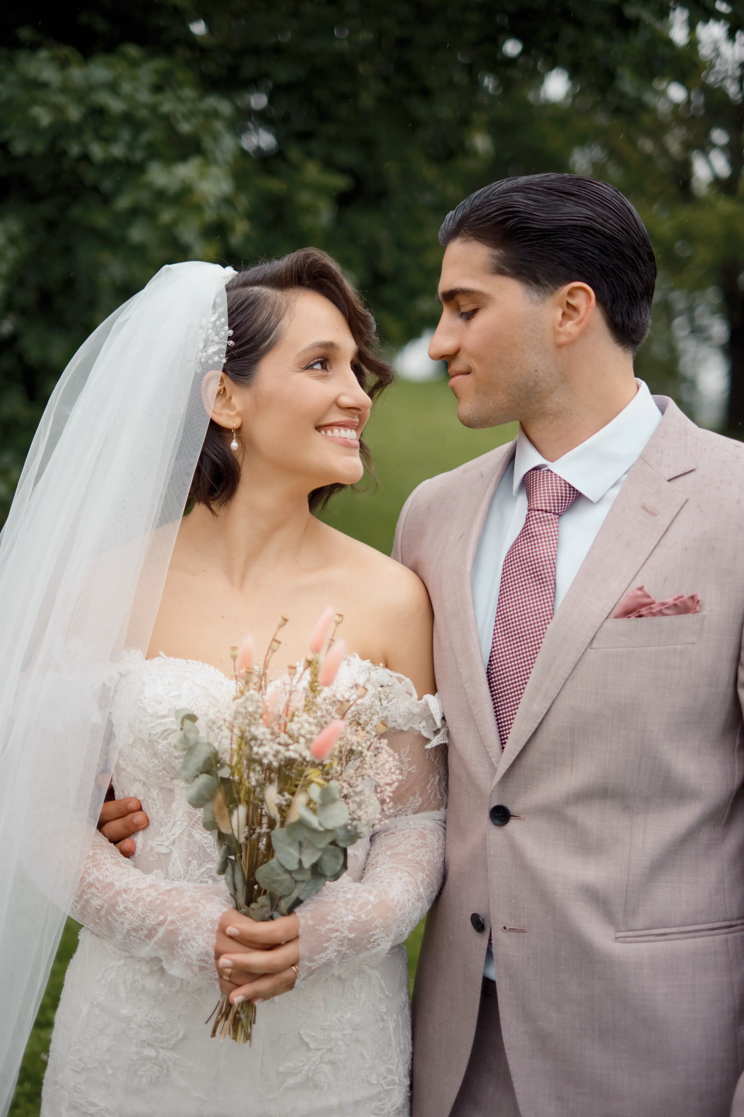 Hochzeitspaar das sich in die Augen schaut, umgeben von grün